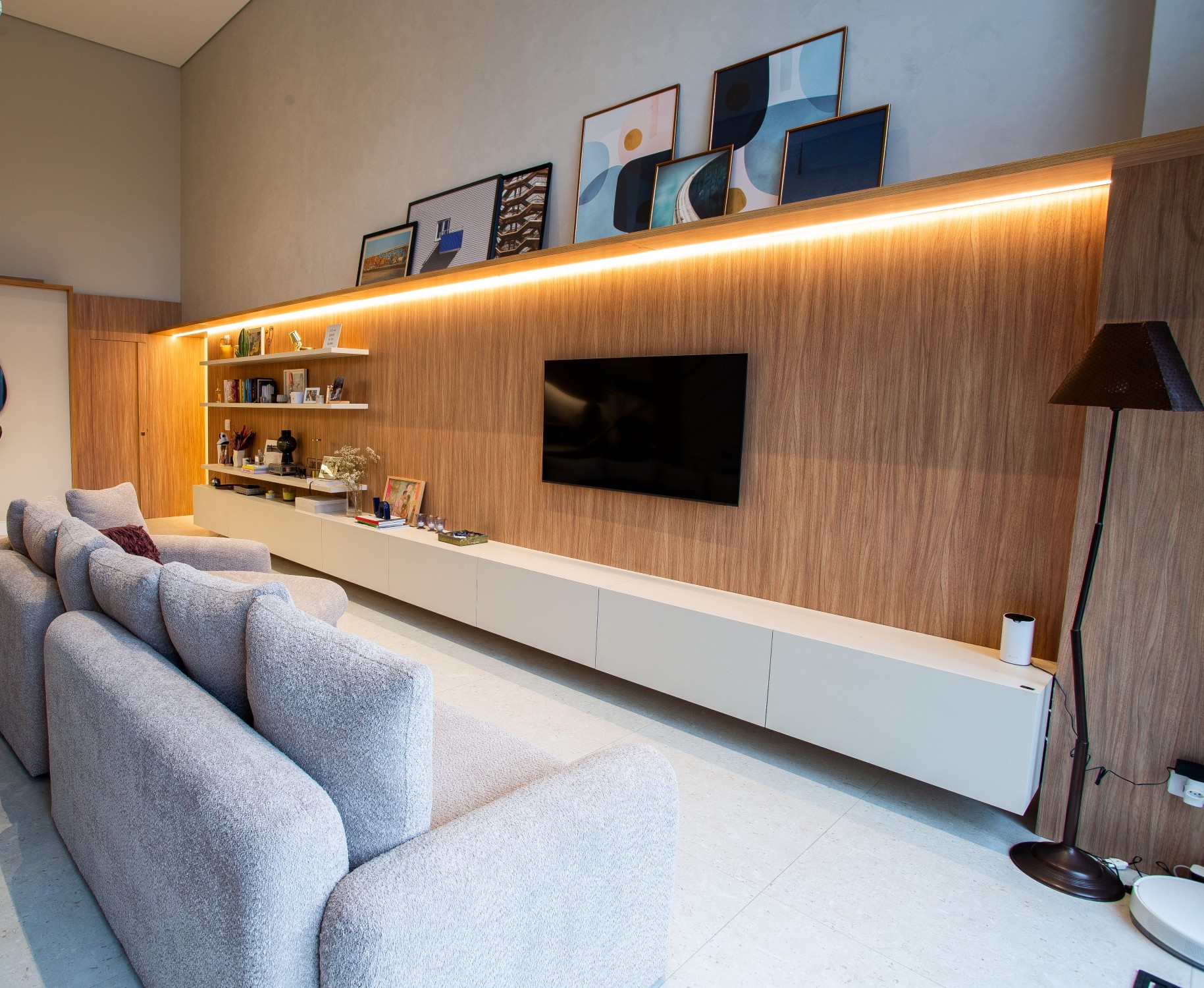 Painel de TV planejado em madeira com iluminação em LED e rack branco suspenso em sala de estar em Curitiba